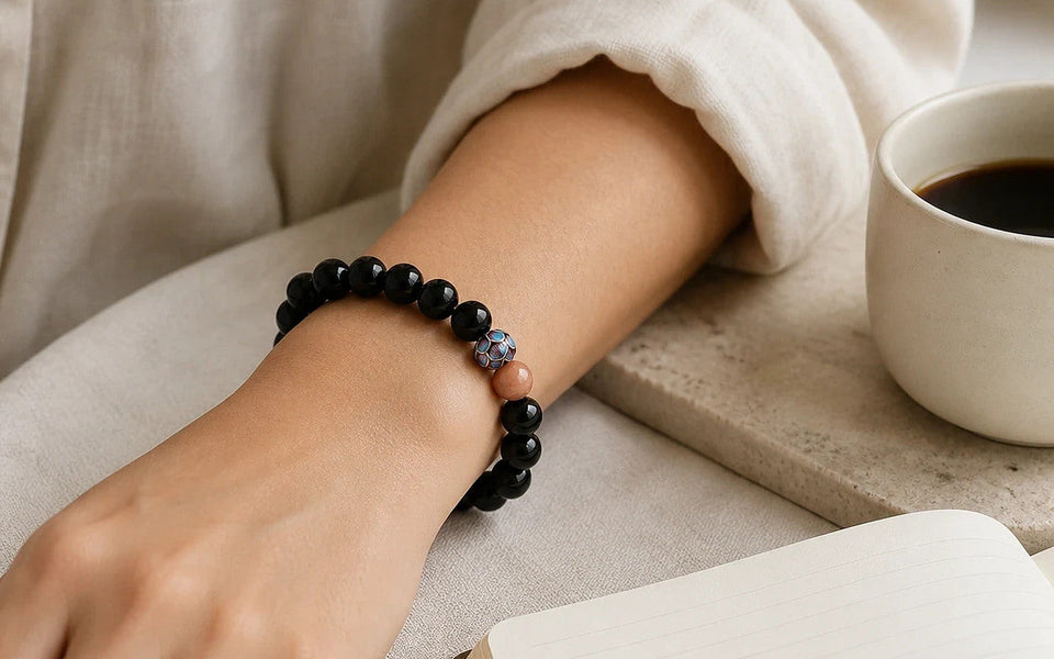 Protection Ritual Bracelet worn at the wrist beside a notebook and coffee
