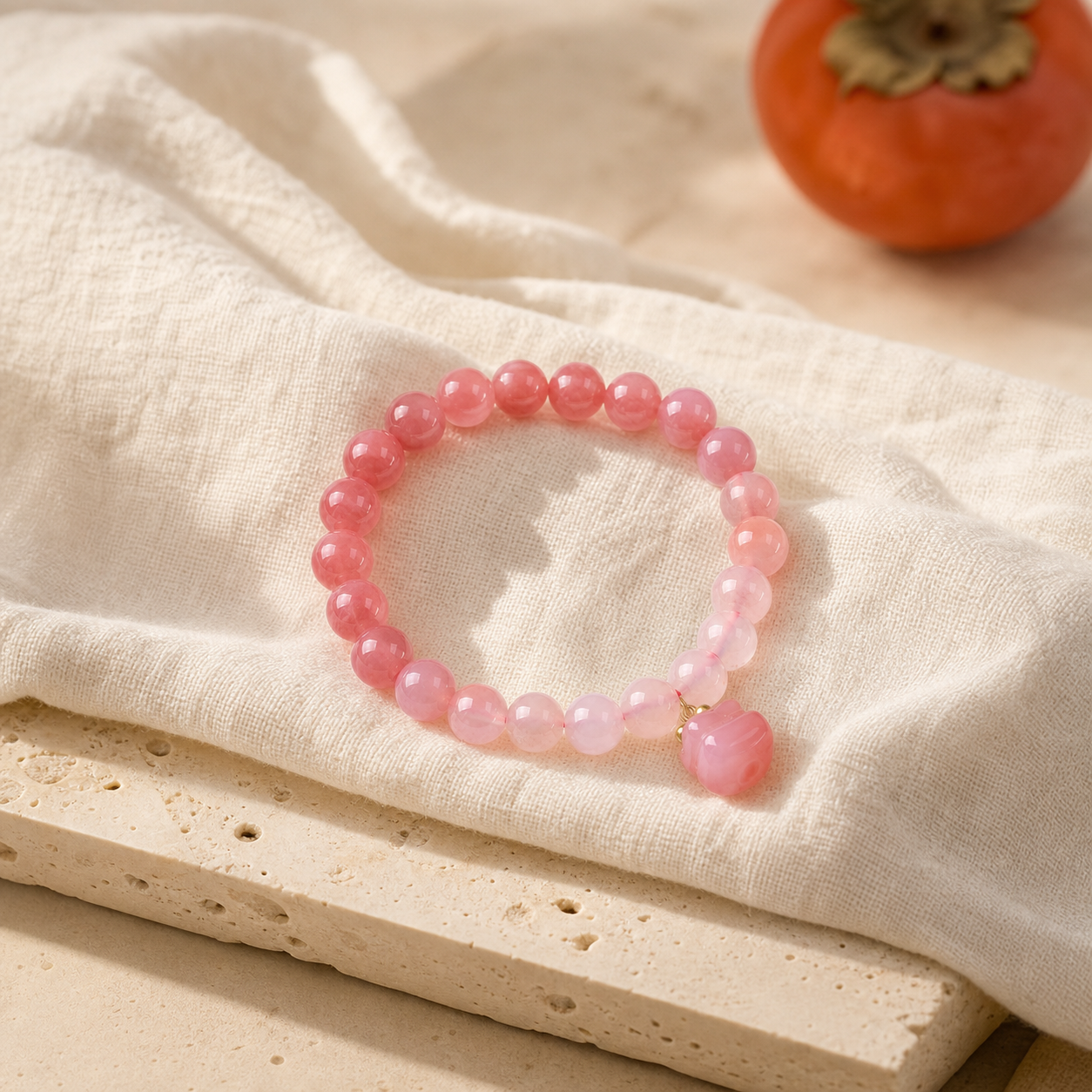 Pink gradient bracelet beside a ripe persimmon